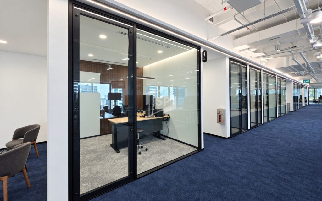 Black-framed glass office partitions and doors along a modern commercial workspace corridor